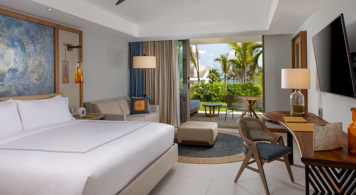 Una habitación de hotel con cama, lámparas y silla con vista al río con balcón