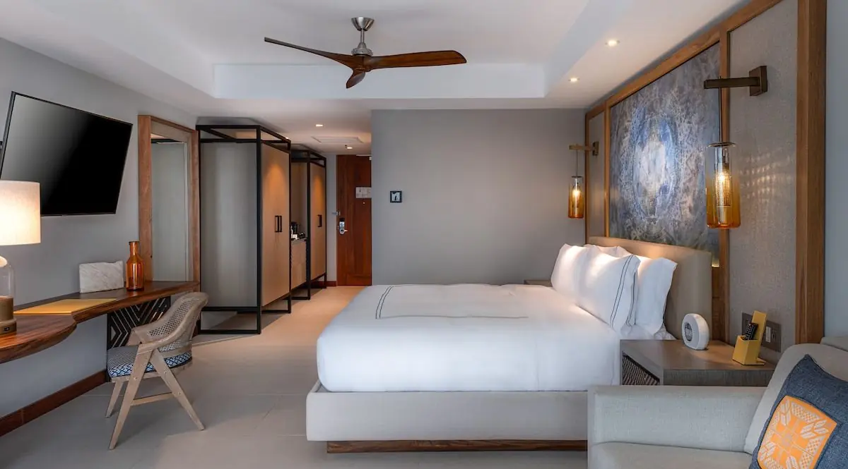 Una habitación de hotel con tv, lámpara, sofá y silla.