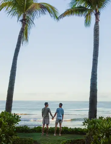 Two men standing and holding their hands near beach