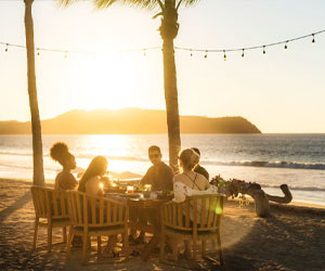 Group of people eating snack food while the sun is setting