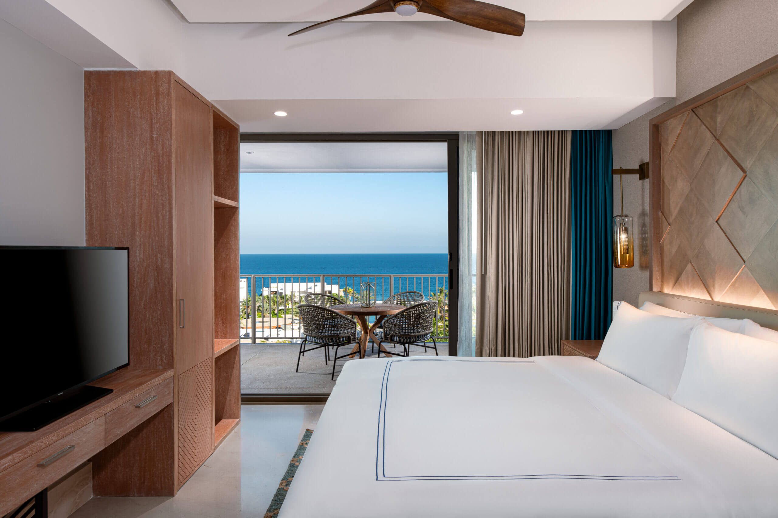 Bed in white sheets, TV and Terrace overlooking the Pacific Ocean