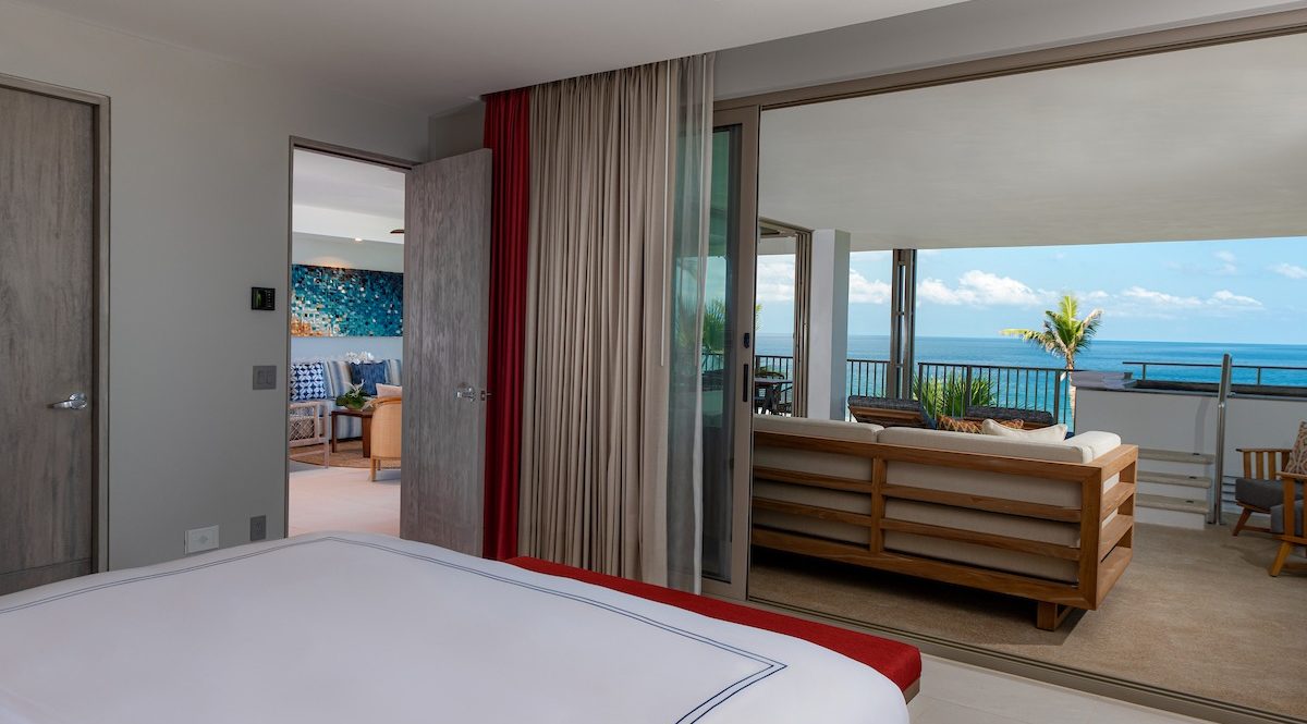 Una habitación de hotel con cama, sofá y silla con vista al río y balcón