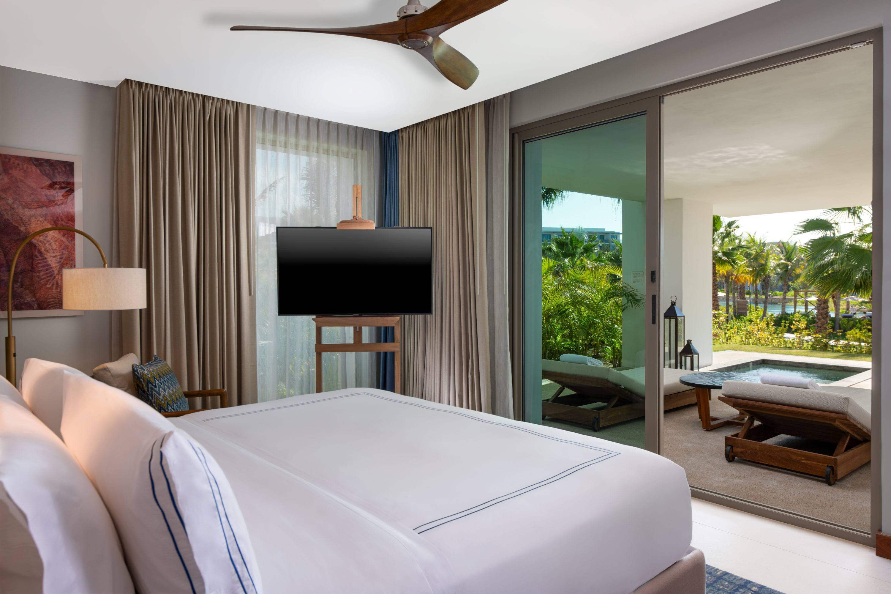 Una habitación de hotel con tv, lámpara con balcón con vista al río.
