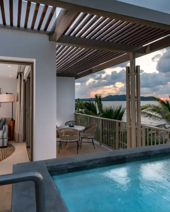 Un balcón de la habitación del hotel con piscina y vistas al río.