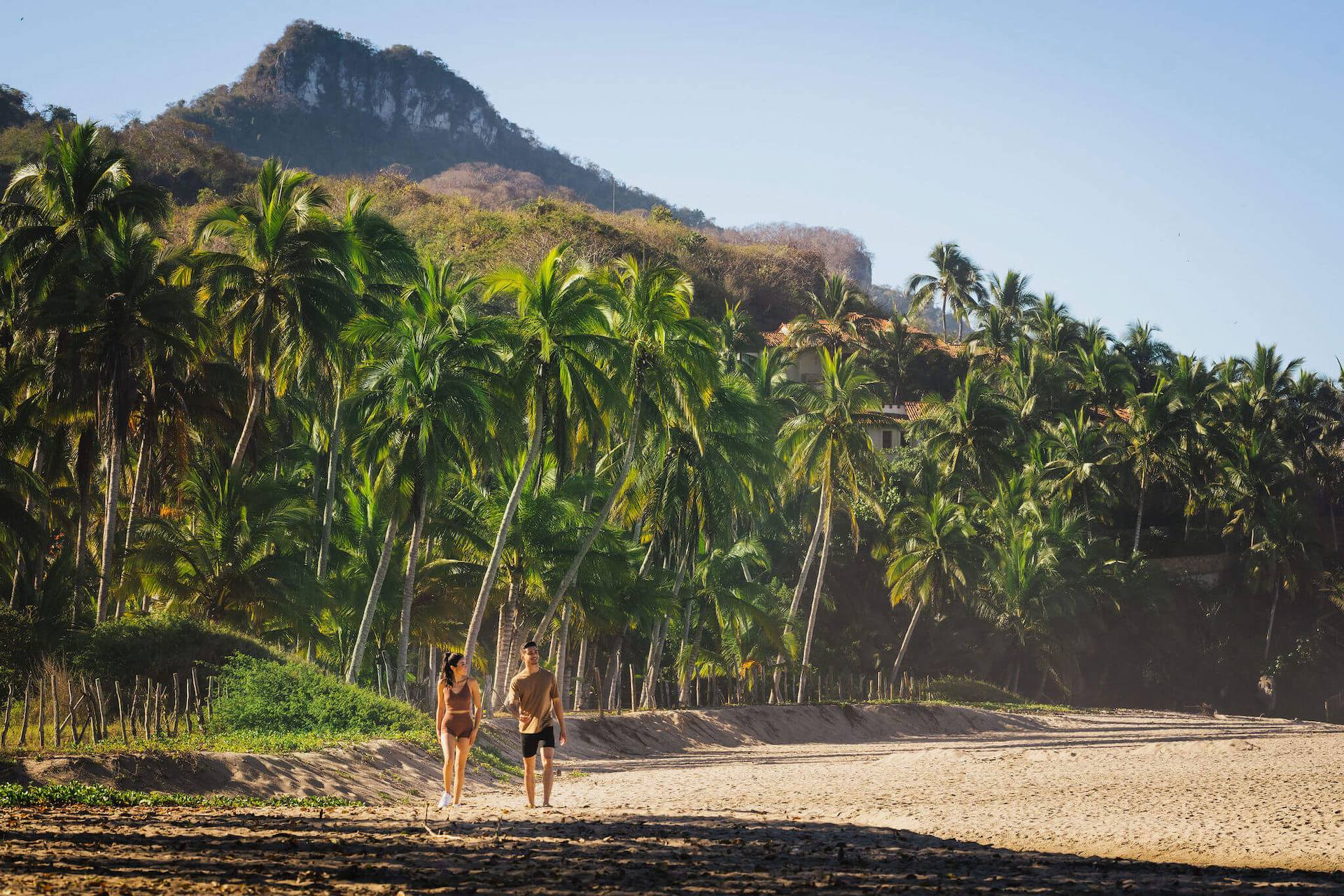 Couple walking on the beach with background of coconut trees