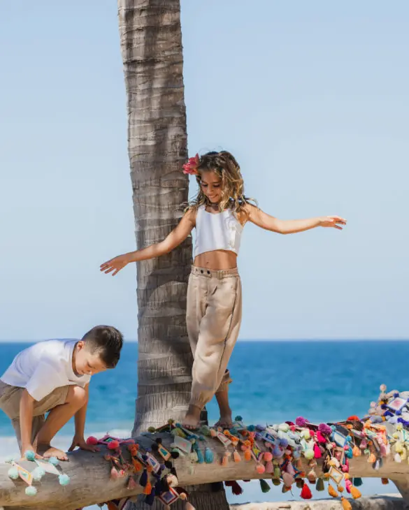 A boy and a girl playing on the fallen ranch of tree