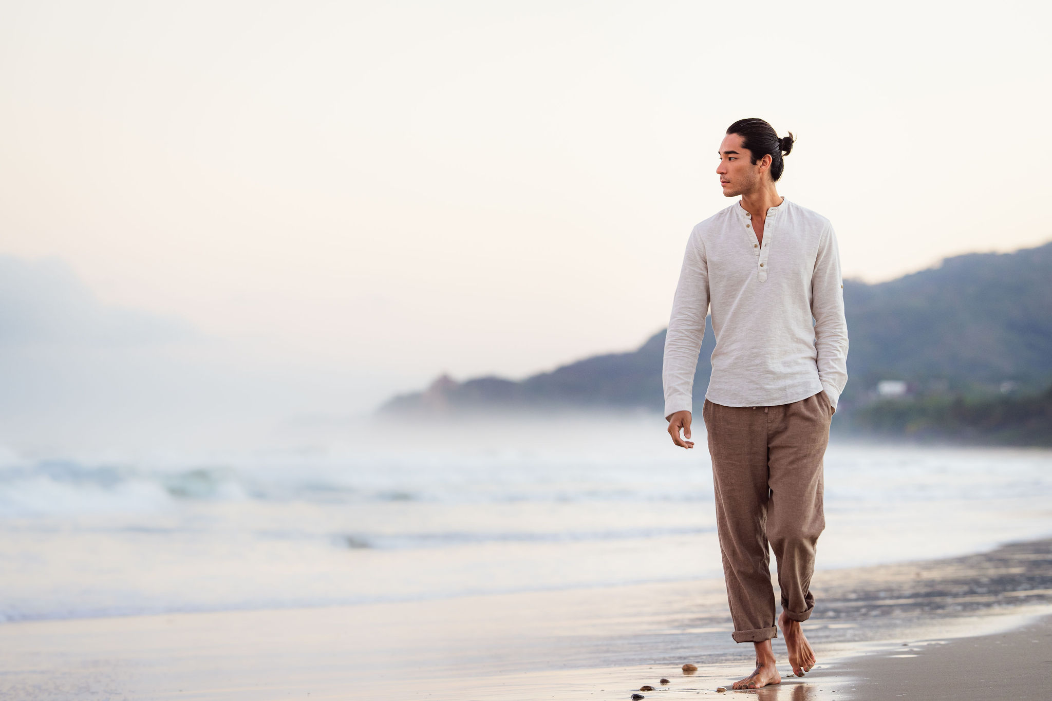 A man in white shirt walking on the beach