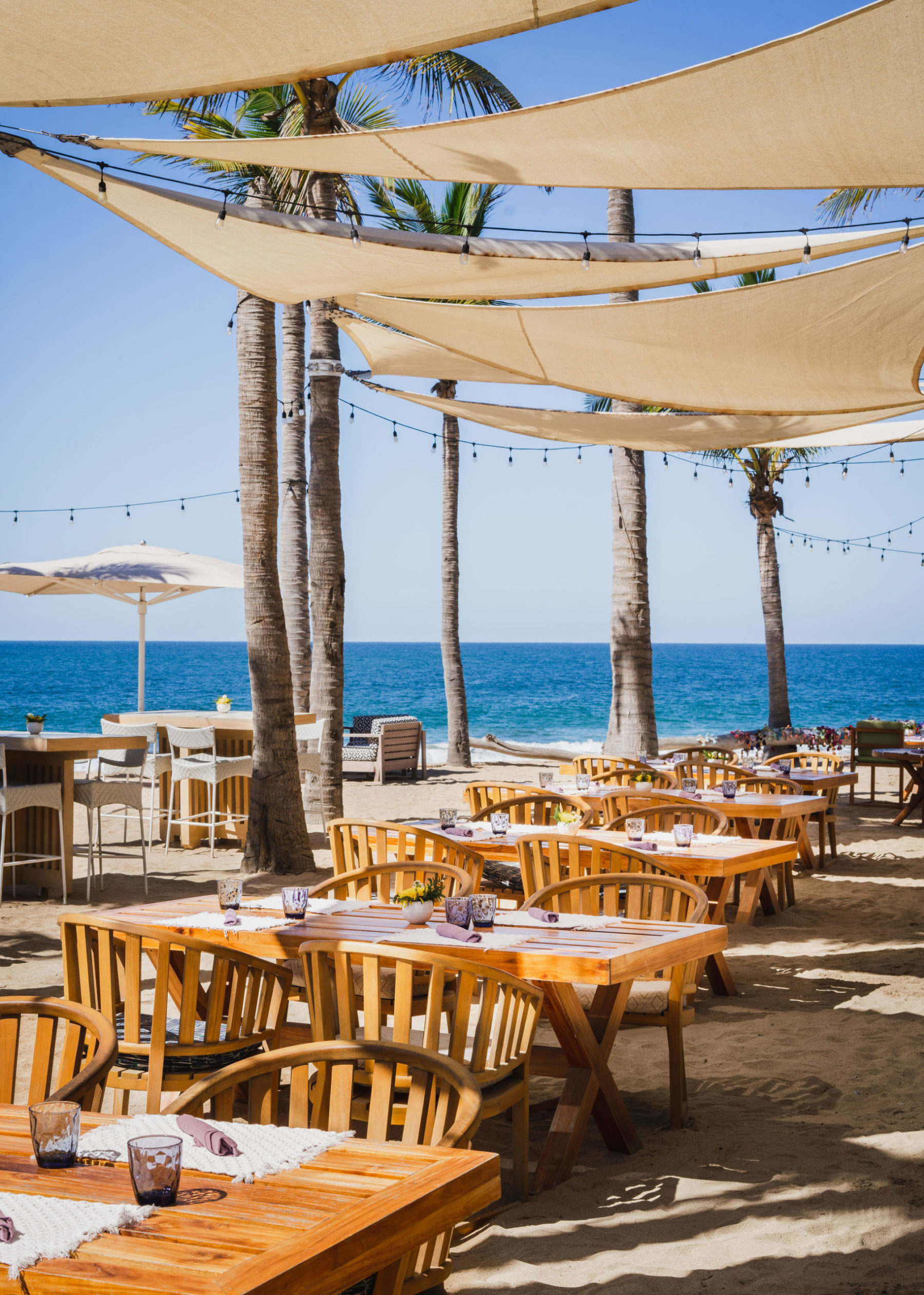 Dining tables on the beach arranged by the restaurant