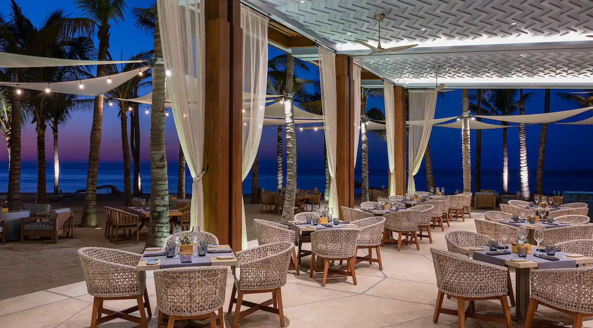 Mesas de comedor en el restaurante al aire libre decoradas con luces en la playa