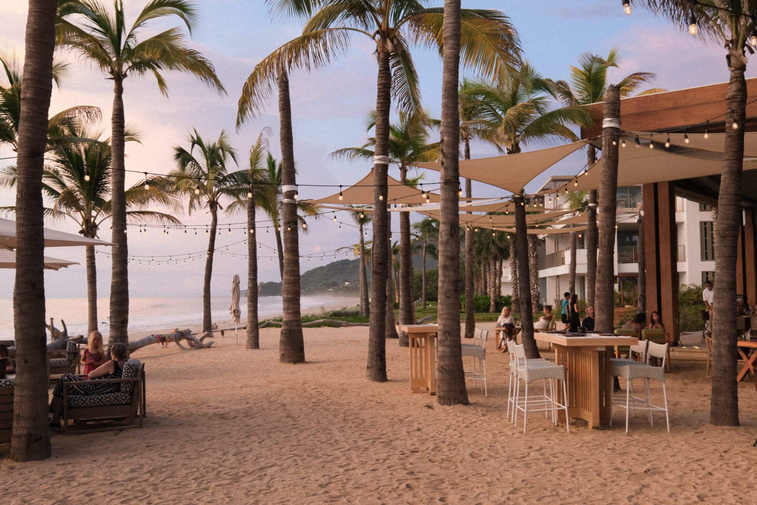 Imagen de playa con iluminación y palmeras.