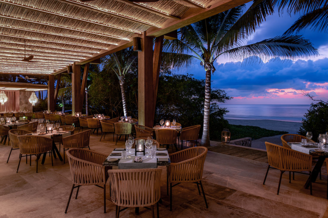 Imagen del restaurante al aire libre con vistas al jardín y al mar.
