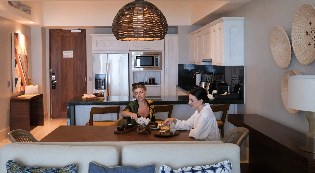 Two people dining in a cozy, modern kitchen with woven decor and warm lighting.
