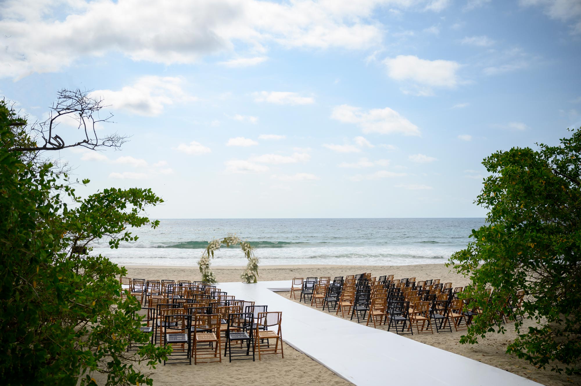 A beautiful wedding setup is arranged on the beach sand with a stunning sea view.