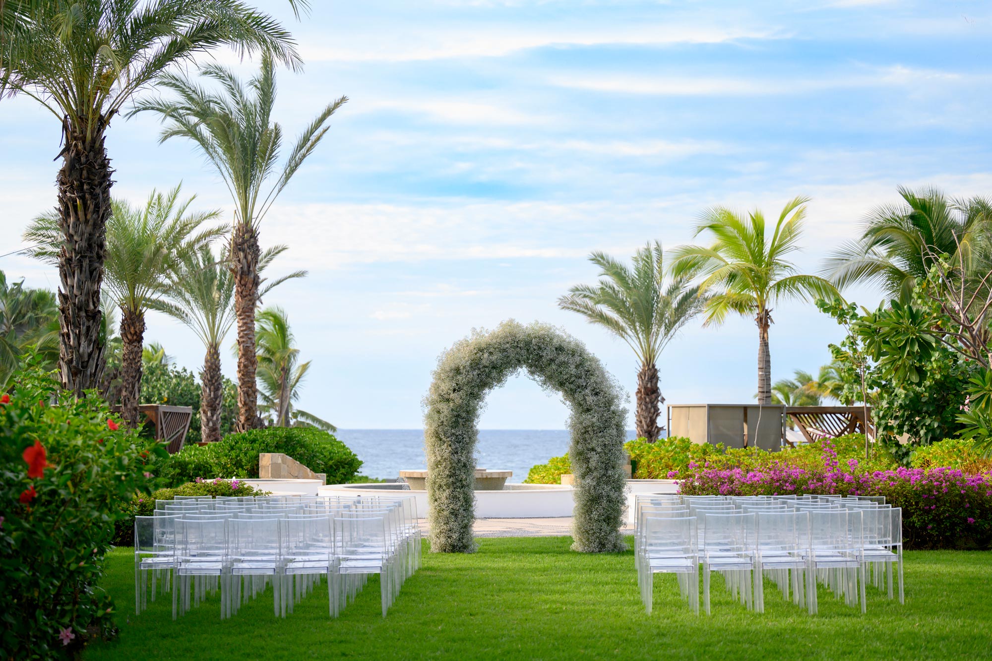 A beautiful wedding setup is arranged on the lawn, offering a stunning sea view.