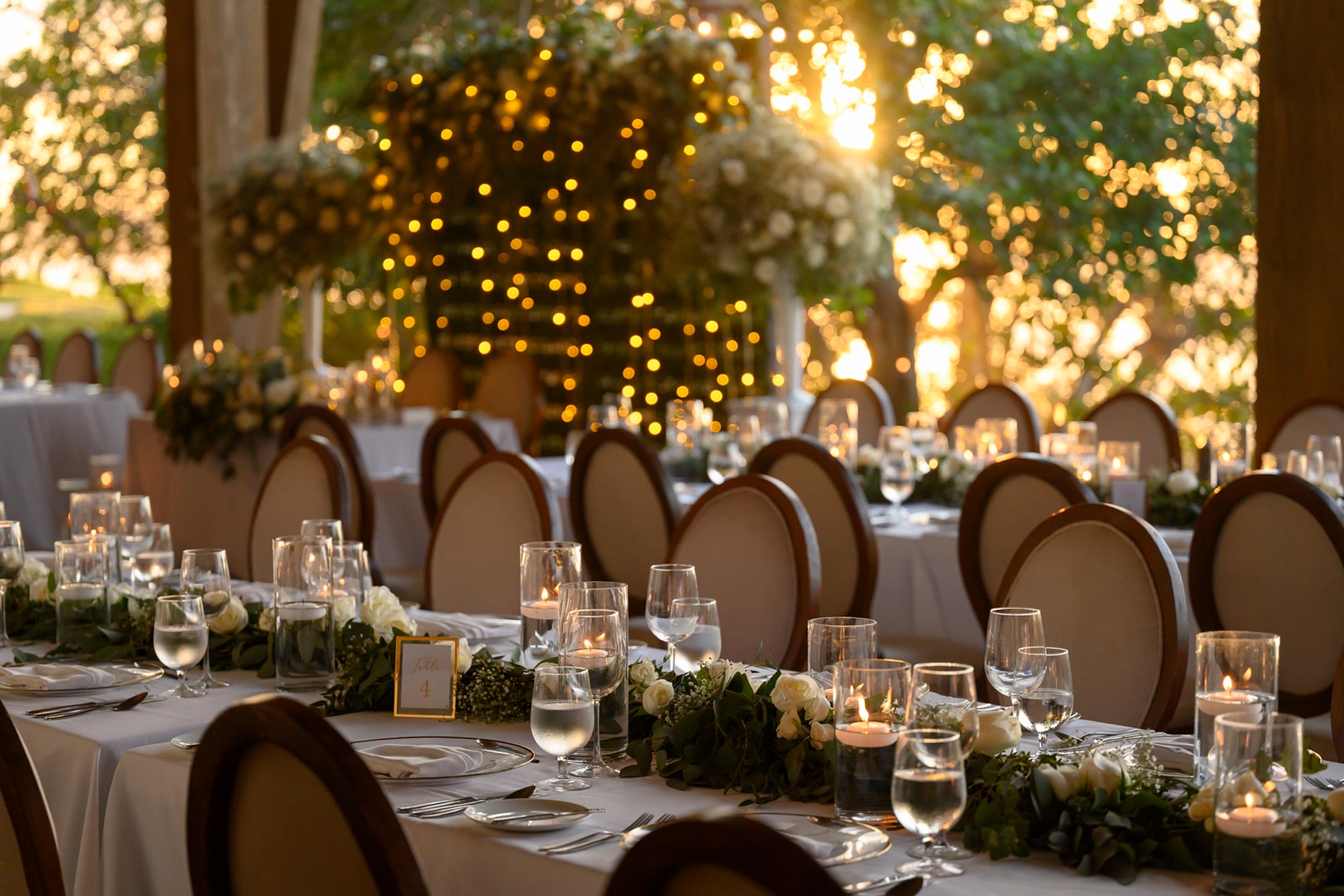 A long table is elegantly adorned with flowers, candles, and crockery for the wedding celebration.