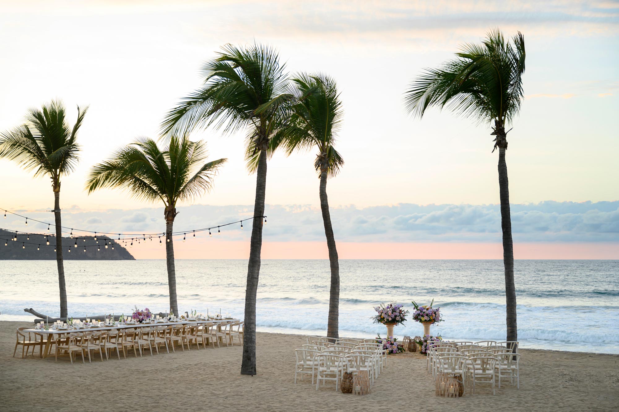 A beautiful wedding setup is arranged on the beach, offering a stunning sea view.