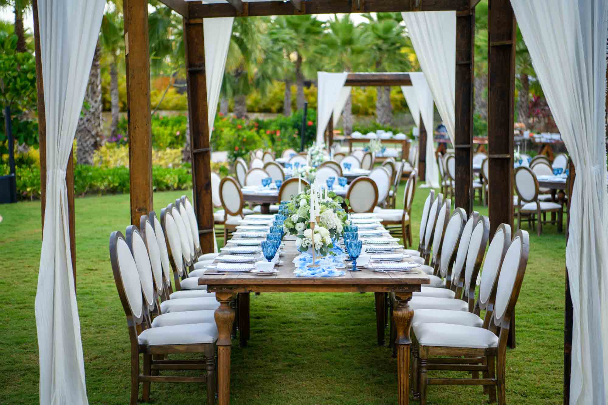 Beautifully arranged long dining table set up in the lawn for wedding dinner celebration.