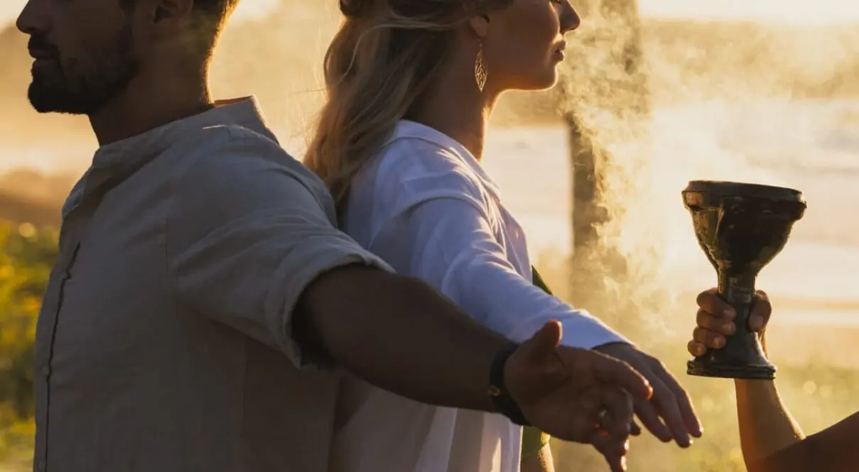 A couple with their backs to each other in a spiritual and romantic ceremony at sunset