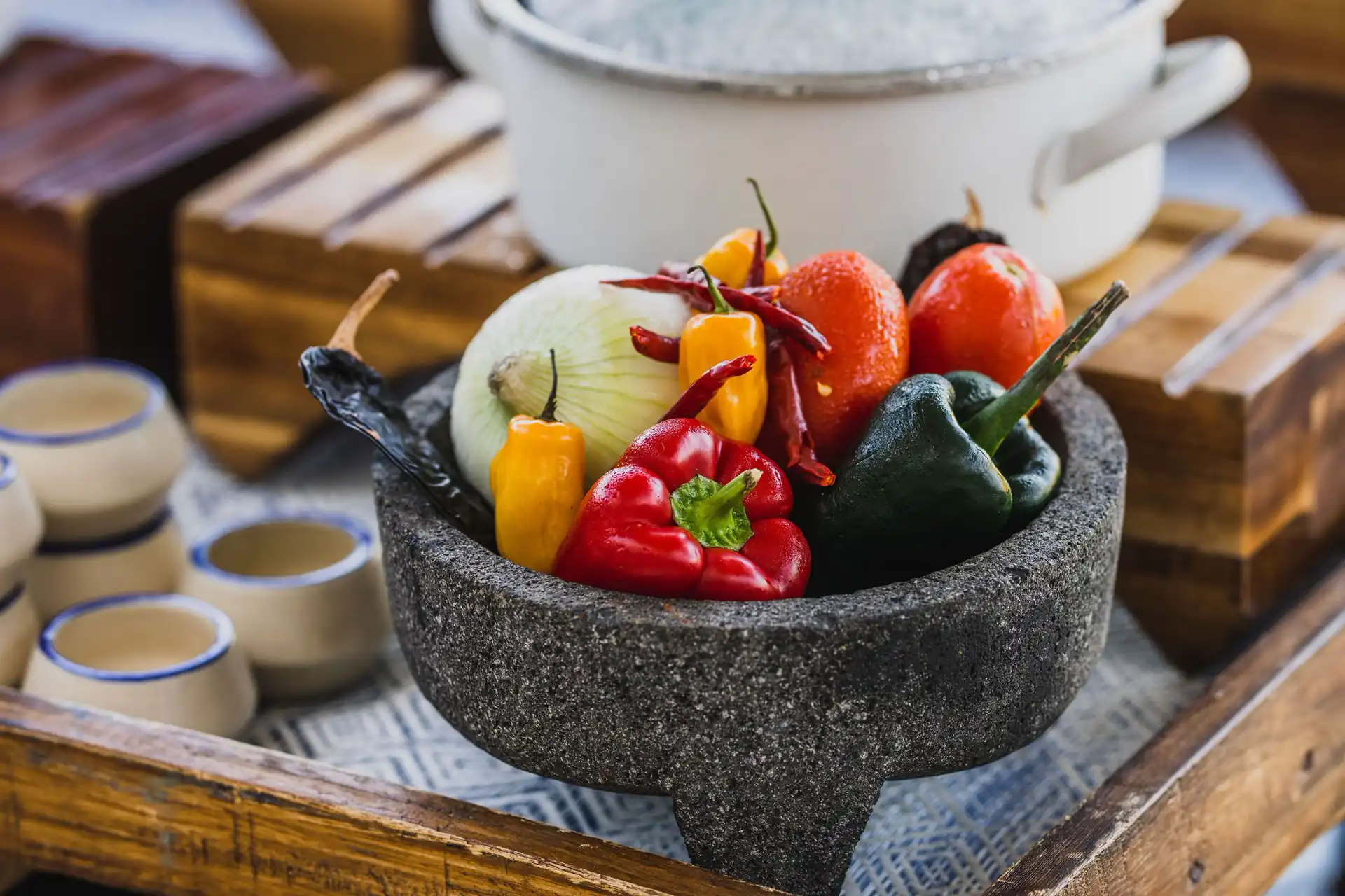 A charcoal bowl on a tray with red and green chili, onion, and tomatoes.