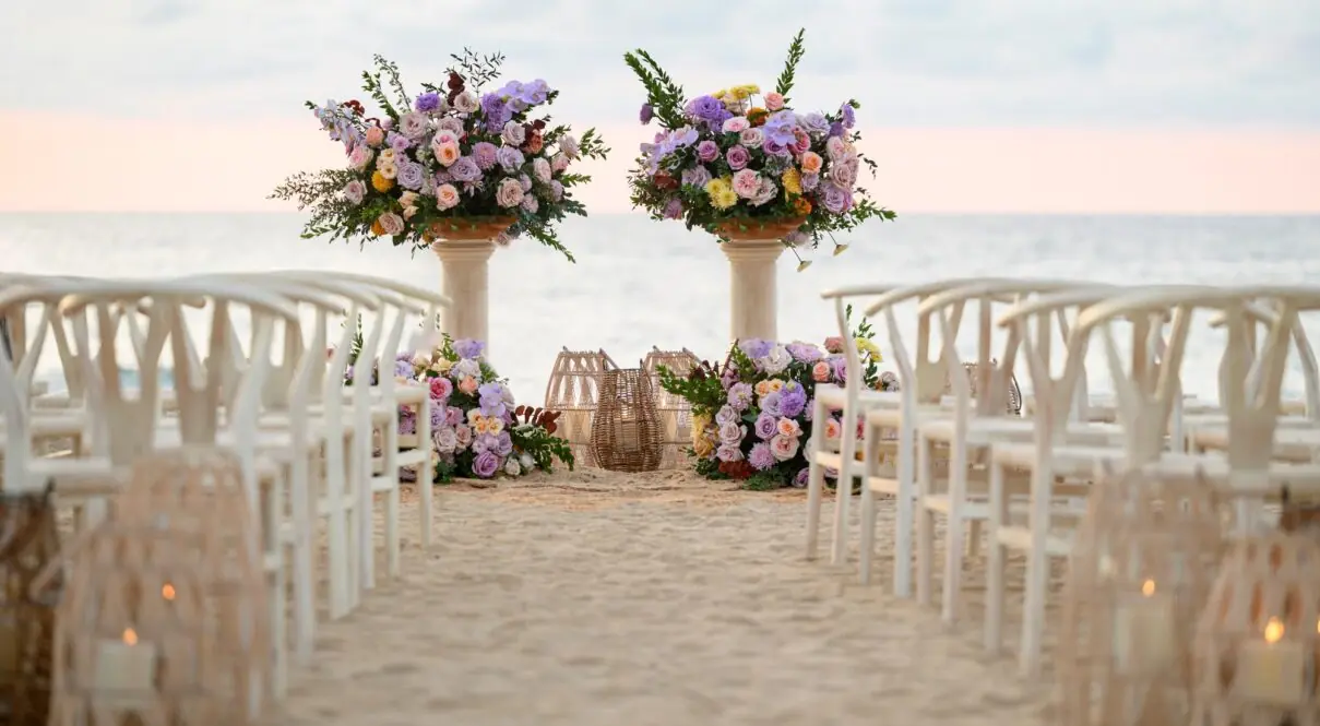 A wedding setup features two long flower vases on the beach with a stunning sea view.
