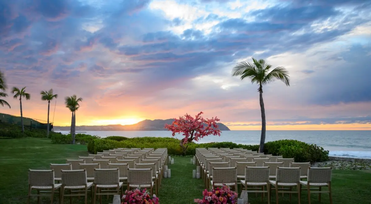 A beautiful wedding setup on the beach sand features a stunning sunrise and sea view.