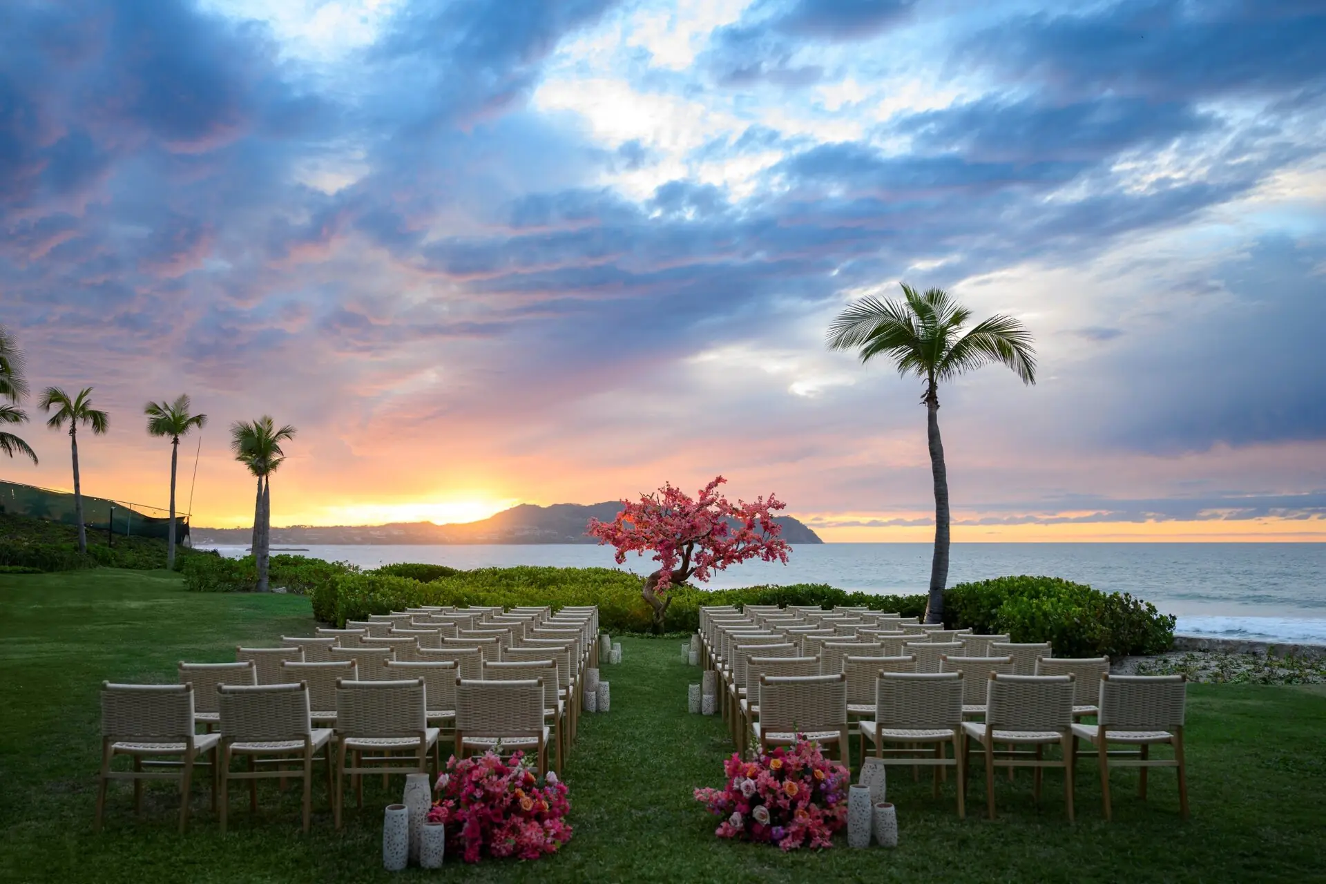 A beautiful wedding setup on the beach sand features a stunning sunrise and sea view.