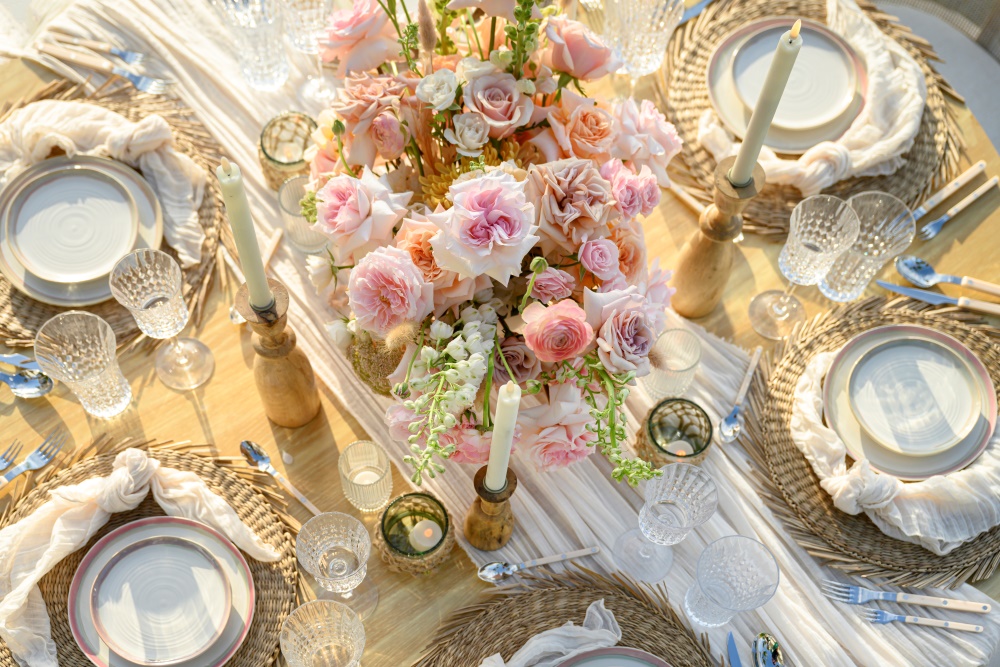 A table is beautifully decorated with flowers, candles, and crockery for the evening celebration.