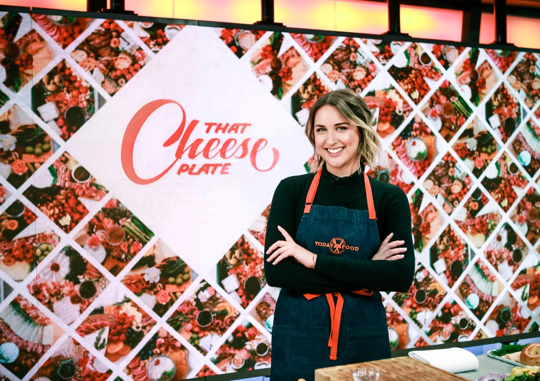 A beautiful lady in an apron stands behind the counter at "THAT Cheese Plate."