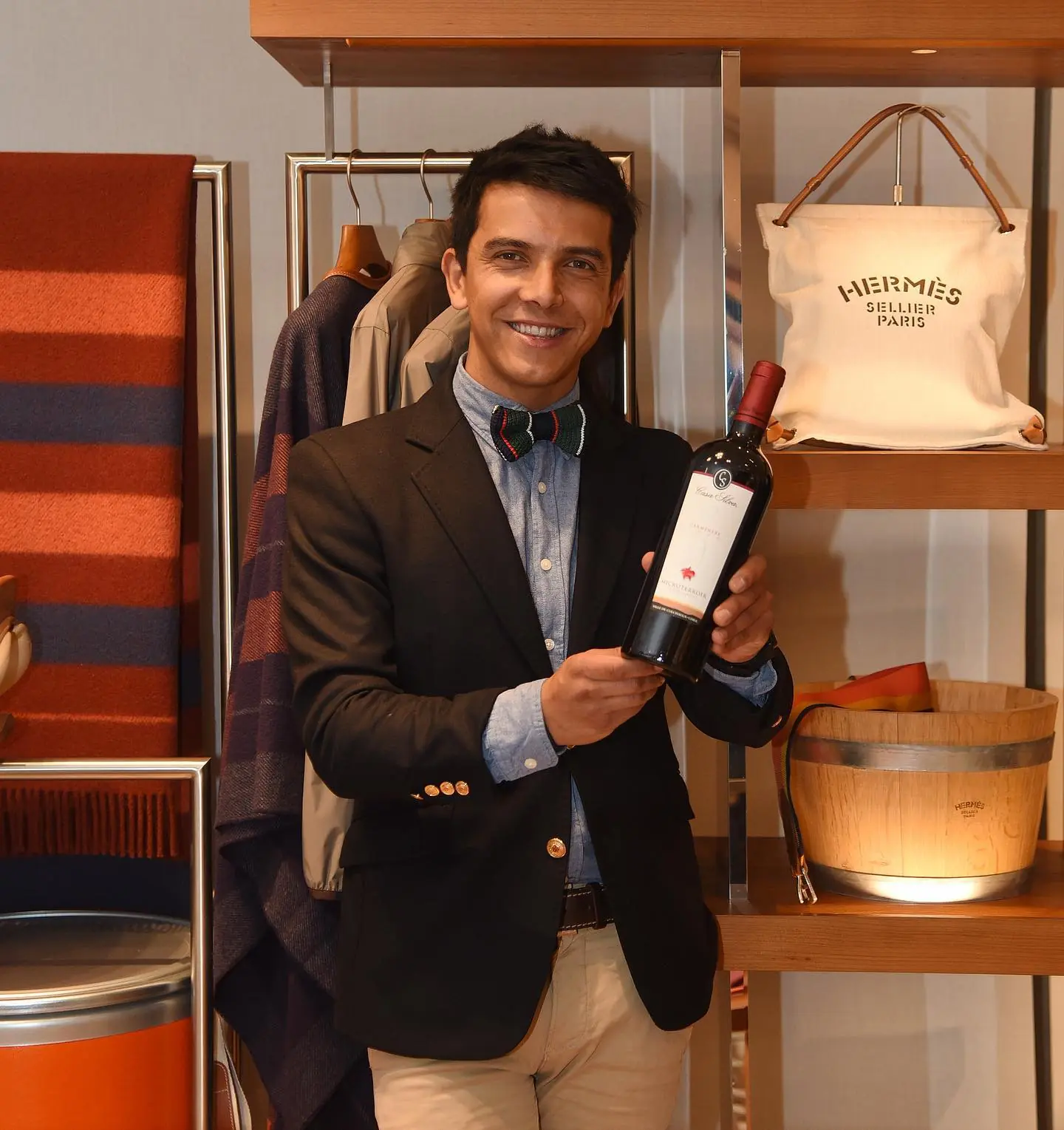 A well-suited man displays a bottle of Marcelo Pino wine with pride.