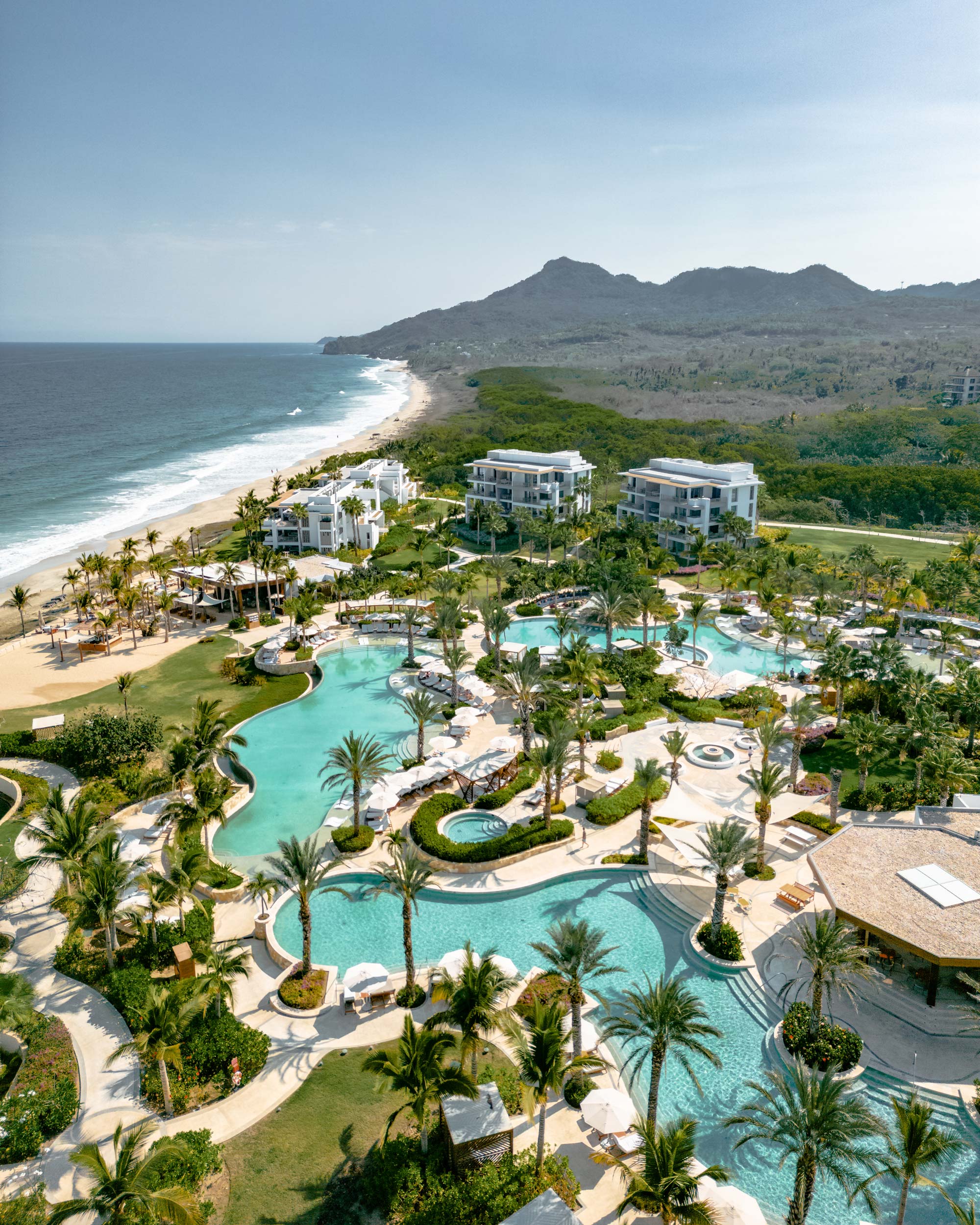 An aerial photograph captures the Conrad Punta de Mita resort with a stunning sea view.