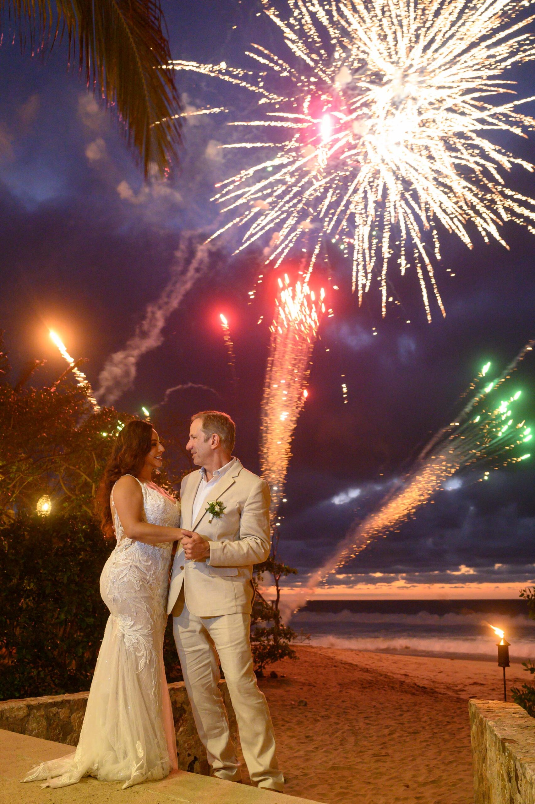 A couple enjoys their wedding on the beach with sparkling fire in the sky.