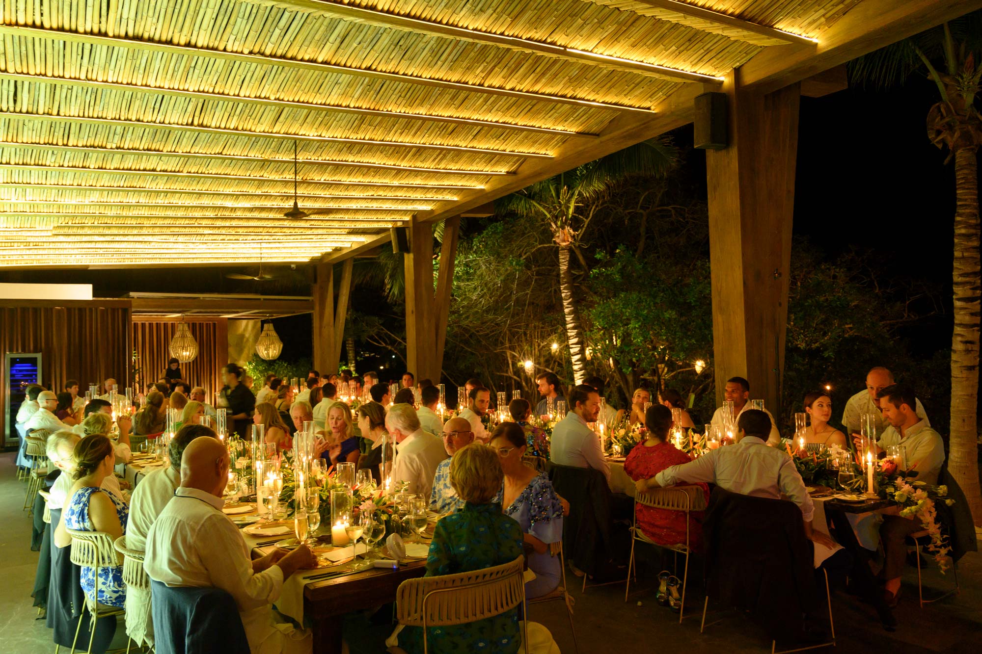 People are enjoying the wedding dinner, surrounded by charming golden light ambiance.