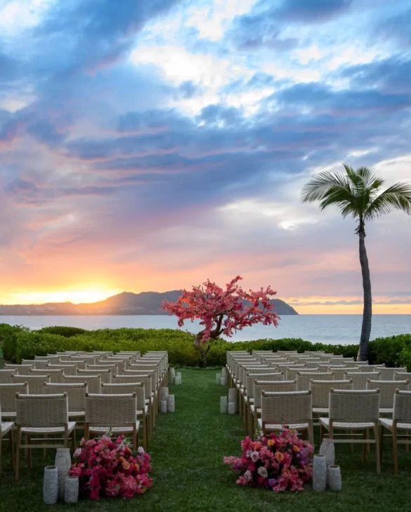 A beautiful wedding setup on the beach sand features a stunning sunrise and sea view.