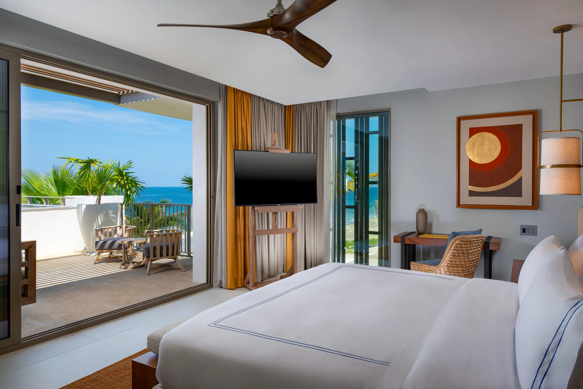 A hotel room with lamp, chair, table tv and having river view with balcony.
