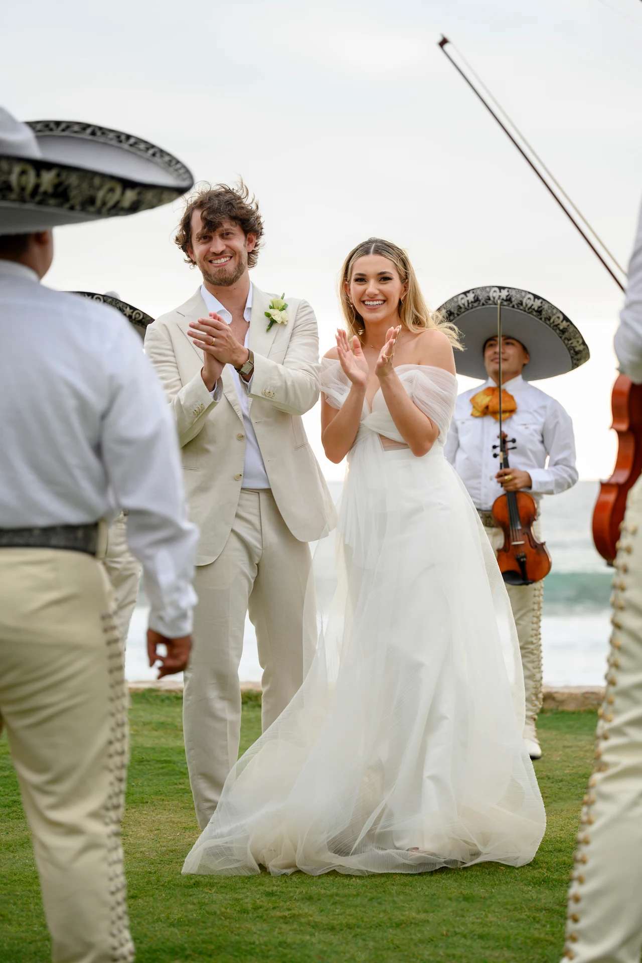 Los novios celebran con una banda de mariachis cerca del agua, combinando música tradicional con alegres momentos de boda.